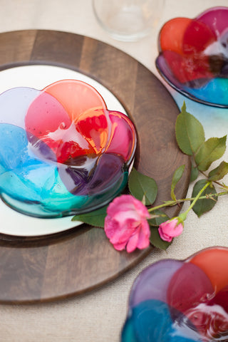 three fused glass bowls in a floral shape in shades of pink, peach, purple and blue hand made by people with disabilities